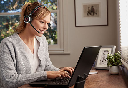 Woman working on a laptop at home wearing Jabra Evolve 65 headset