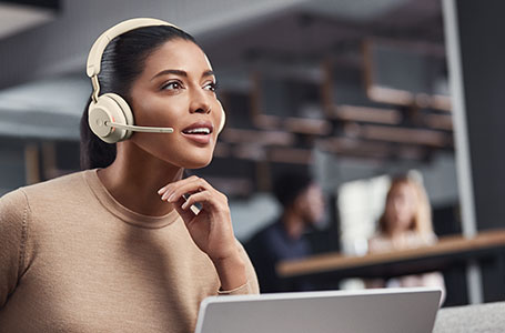 Woman wearing beige Evolve2 65 headphones taking a call