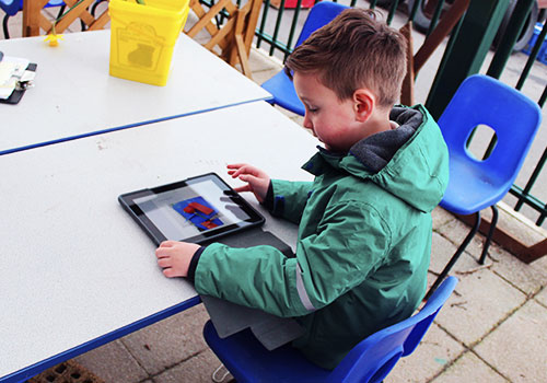 Boy outside using iPAd for science