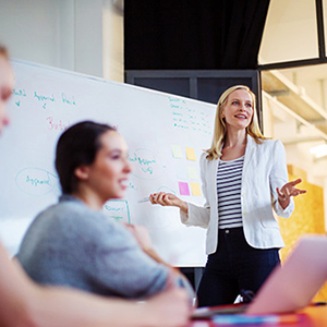 Female educator enthusiastically presenting in a learning environment with a whiteboard