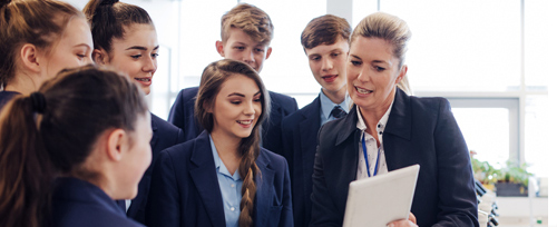 Teacher with tablet device and school children