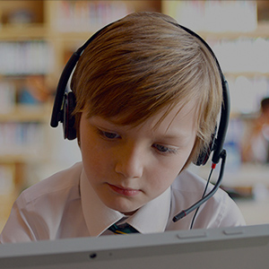 Young male student using headset in classroom